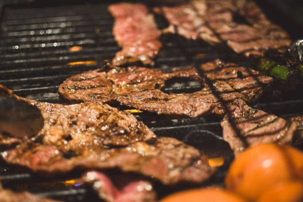 Deliciously grilled steaks over a barbecue with tomatoes. Perfect for outdoor cooking enthusiasts.